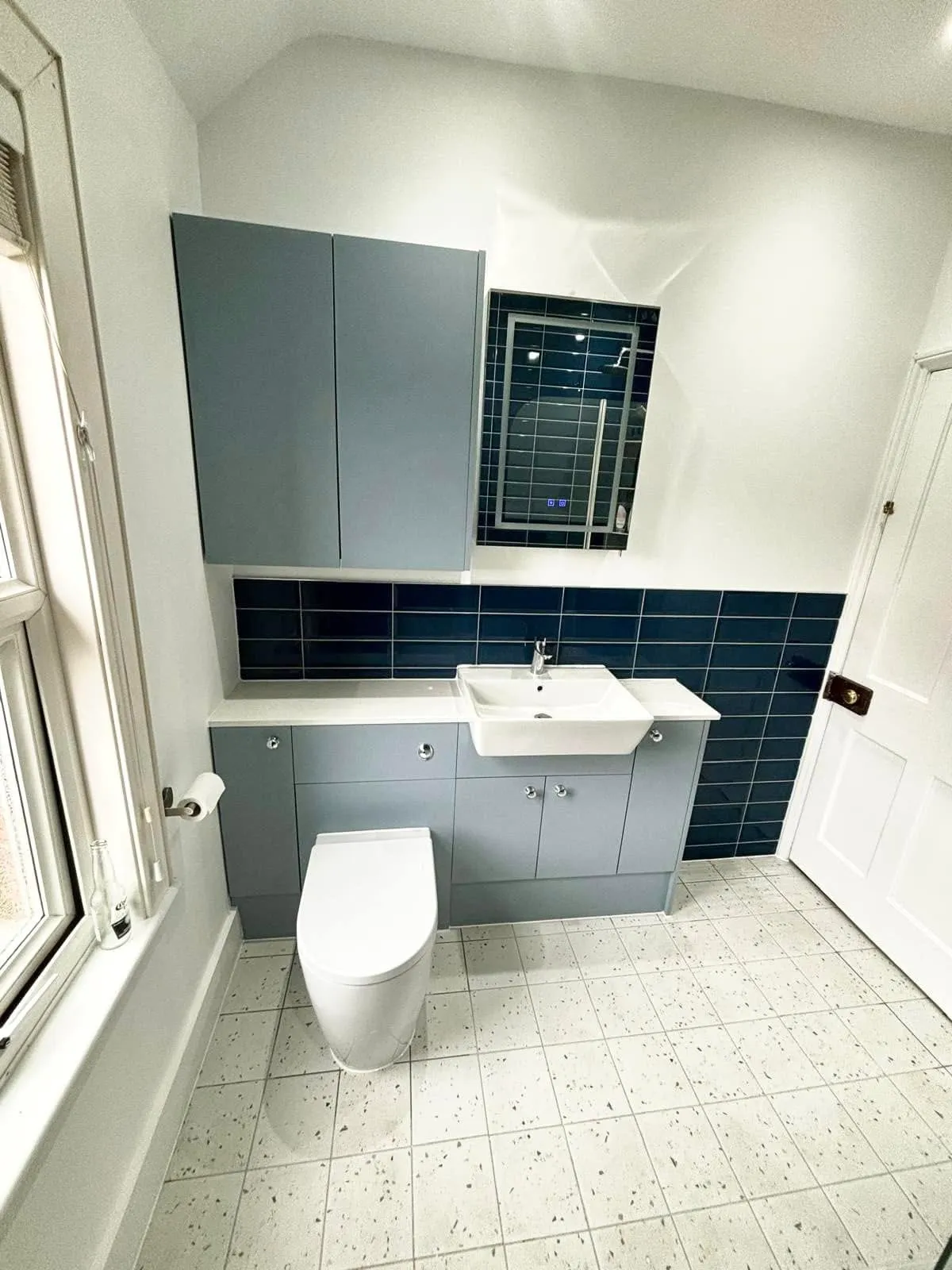 A white toilet sitting next to a window in a bathroom.