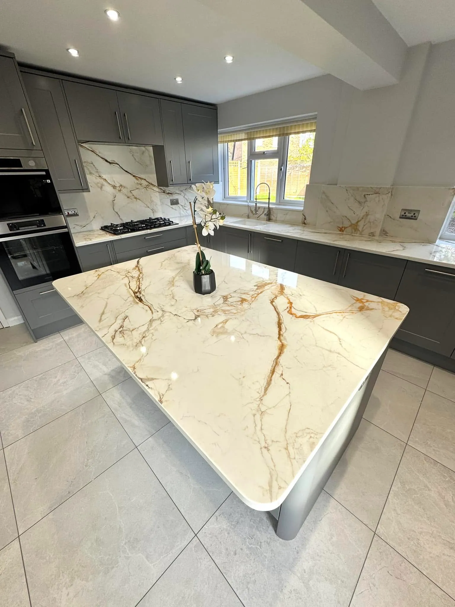 A kitchen with a marble counter top next to a stove top oven.