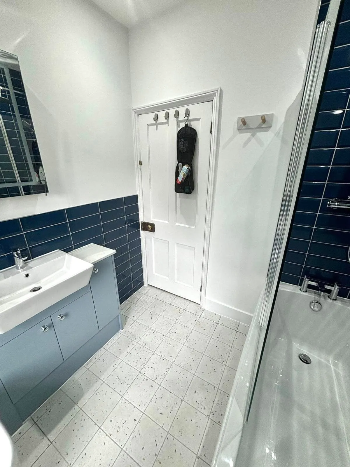 A bathroom with a sink, mirror, and bathtub.